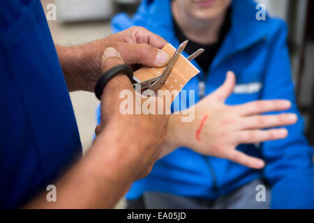 Factory worker applying first aid to colleague Stock Photo