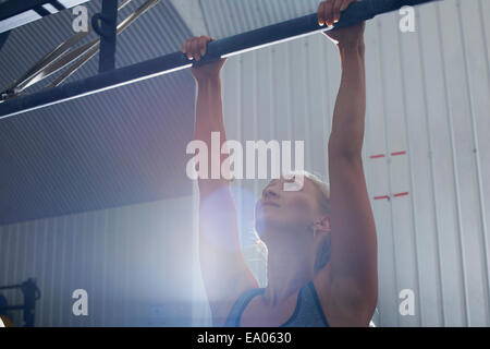 Woman doing pull ups in gym Stock Photo