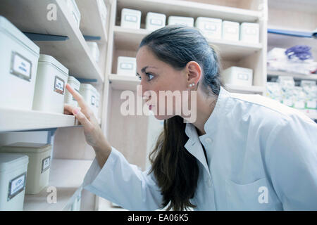 Pharmacist in pharmacy looking at storage tin Stock Photo