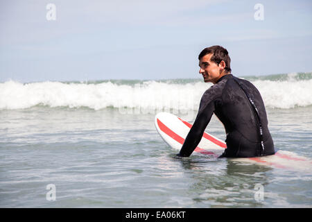Young man sitting on surfboard in sea