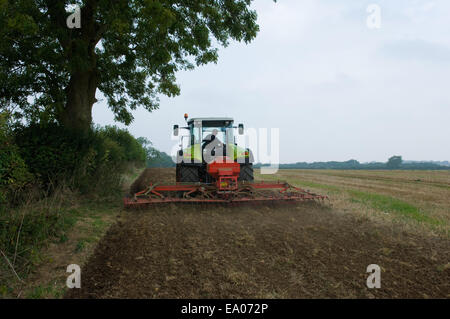 Farmer driving tractor and planting seed corn in field Stock Photo