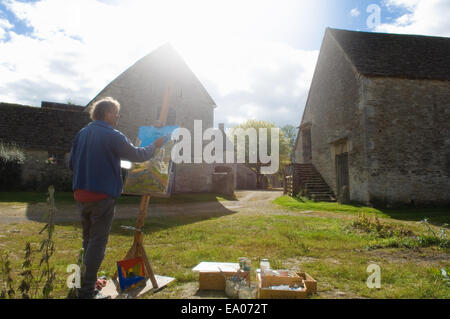 Man oil painting at easel outside farm buildings Stock Photo