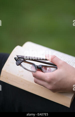 Hand with eye glasses keeping book open Stock Photo