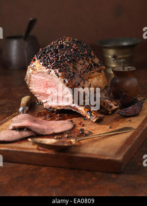 Christmas dinner. Bone in sirloin joint with peppercorn crust and brandy glaze served with roasted potatoes Stock Photo
