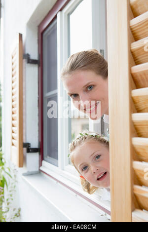 Mother and daughter peering through window Stock Photo