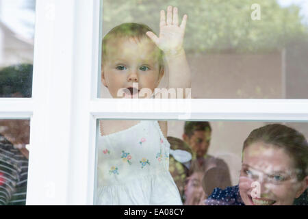 Baby girl and mother looking out of window Stock Photo