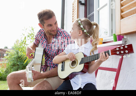 Girl playing guitar with father Stock Photo