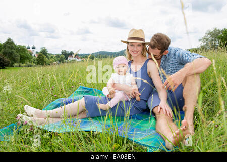 Family sitting on blanket in field, portrait Stock Photo