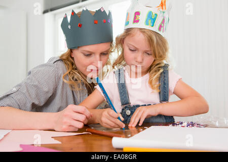 Mother and daughter making paper crowns Stock Photo