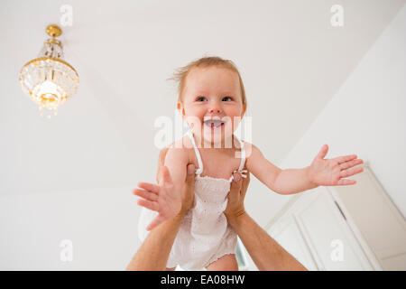 Baby girl being lifted above Stock Photo