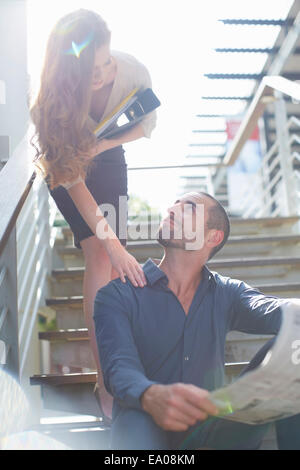 Businesswoman beckoning businessman on staircase Stock Photo