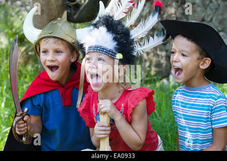 Three children wearing fancy dress costumes, playing in park Stock Photo