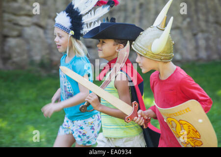 Three children wearing fancy dress costumes, playing in park Stock Photo