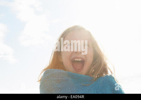 Portrait of laughing girl wrapped in towel at sunlit coast Stock Photo