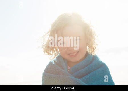 Portrait of girl wrapped in towel at sunlit coast Stock Photo