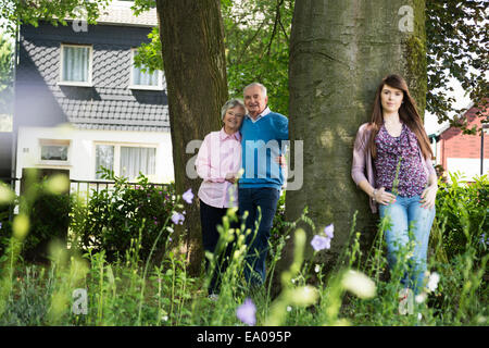 Grandparents and granddaughter standing by tree Stock Photo