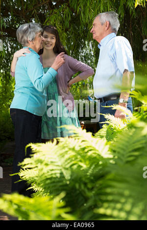 Grandparents and granddaughter having conversation in garden Stock Photo