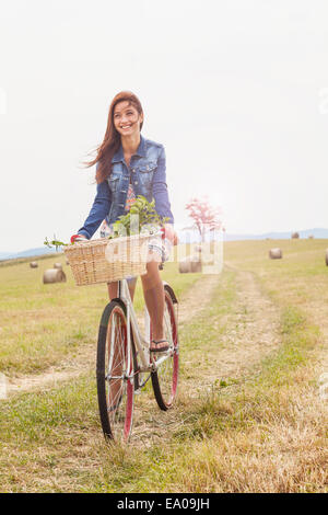 Teenager riding bicycle on field, Roznov, Czech Republic Stock Photo