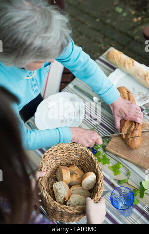 Senior woman cutting bread, high angle Stock Photo
