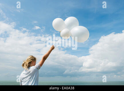 Girl holding white balloons outdoors