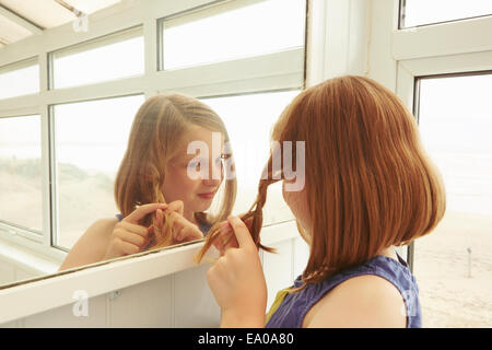 Girl plaiting hair in holiday apartment porch Stock Photo