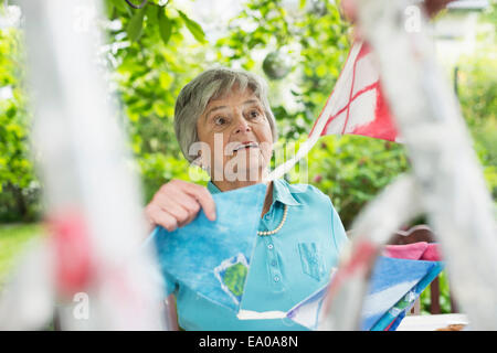 Senior woman hanging up bunting Stock Photo