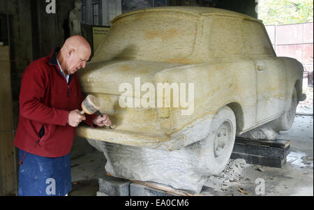 Berlin, Germany. 31st Oct, 2014. Stone sculptor and restorer Carlo Wloch works on a Trabant 601, which he carved out in its original size from a 25 tonne block of sandstone, in his studio in Berlin, Germany, 31 October 2014. He has been working on the GDR car, now weighing 12.7 tonnes, since 1997. The sculpture will be presented on a stretch of the former Wall for the 25th anniversary of the Fall of the Berlin Wall. Photo: Jens Kalaene/dpa/Alamy Live News Stock Photo