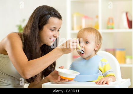 Mom spoon feeds child Stock Photo
