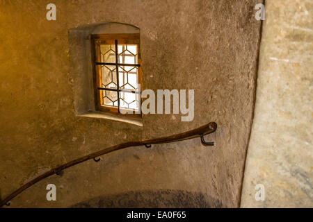 Medieval window with wooden frame and iron grating in Prague. Ancient stone walls, wooden handrail on large stairs Stock Photo