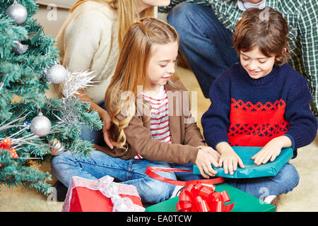 Girl and boy opening christmas gifts together at christmas eve Stock Photo