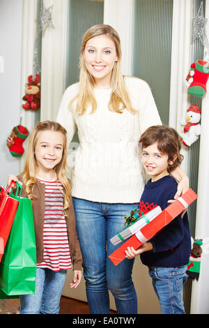 Happy mother with daughter and son carrying many christmas gifts Stock Photo