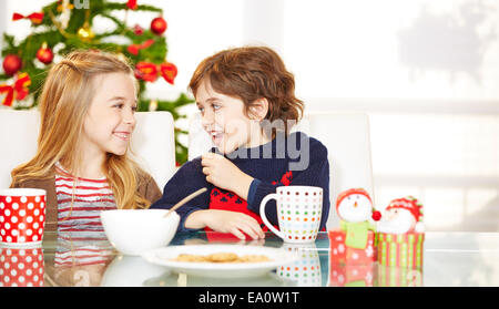 Two happy children eating cookies at christmas at the table Stock Photo