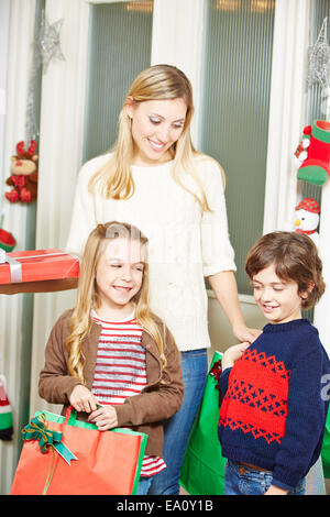 Happy mother and smiling children carrying many christmas gifts Stock Photo
