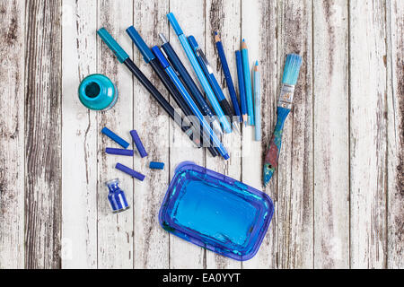 Still life of blue paint brush, crayons and colored pencils Stock Photo