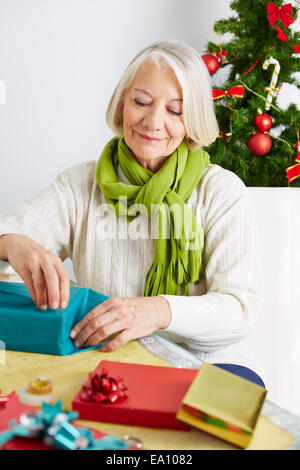 Senior woman wrapping gifts for christmas with wrapping paper Stock Photo