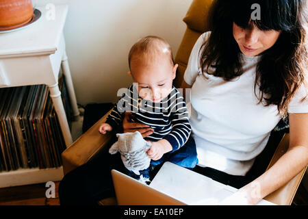 Mother using laptop with son on lap Stock Photo