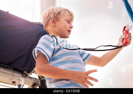 Low angle view of boy on sailboat using a weather and wind meter Stock Photo