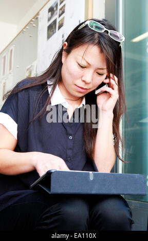 Female architect using smartphone and digital tablet on office step Stock Photo