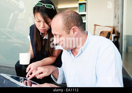 Male and female architects looking at digital tablet in office