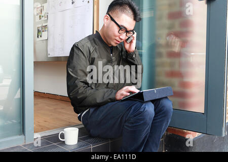 Male architect using smartphone and digital tablet on office step Stock Photo