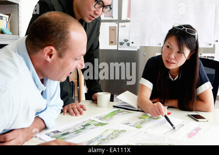 Team of three architects discussing ideas for blueprint in office Stock Photo