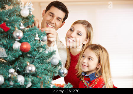 Happy family decorating christmas tree together at home Stock Photo