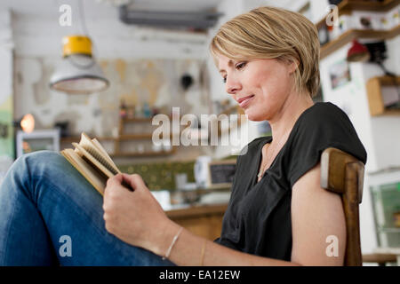 Mid adult woman reading book in cafe Stock Photo