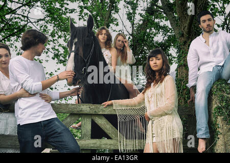 Portrait of six young adults and horse at forest gate Stock Photo