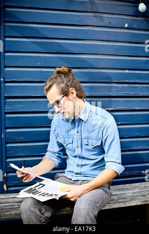 Young man looking at print outs of designs outside Stock Photo