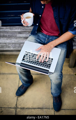 Man using laptop on bench Stock Photo
