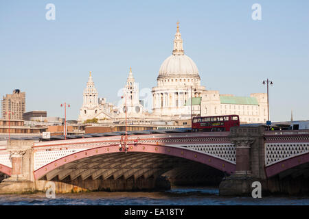 Red London double decker bus going over Blackfriars Bridge with St Pauls cathedral and views of London in October Stock Photo