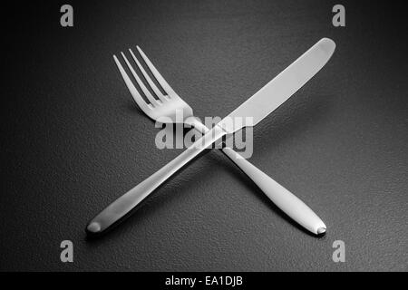 crossed knife and fork on black Stock Photo