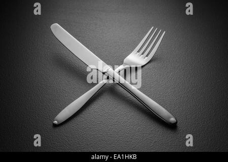 crossed knife and fork on black Stock Photo