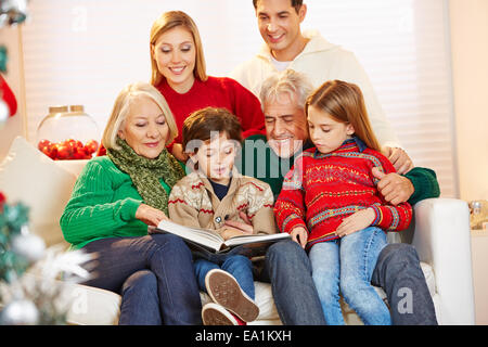 Grandparents reading book to grandchildren at christmas Stock Photo